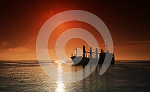 Silhouette of the cargo ship over the sunrise