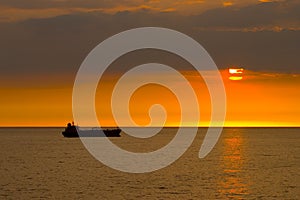 Silhouette of the cargo ship over the sunrise.