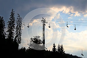 Silhouette of a chairlift over a forest on a mountain slope photo
