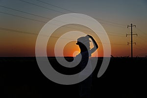 Silhouette of a child. the boy put his hand to his head against the backdrop of the setting sun