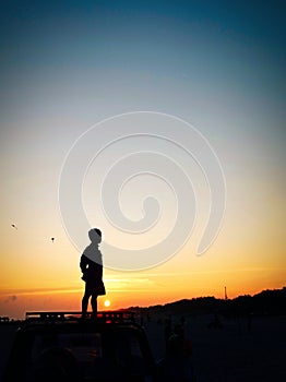 The silhouette of a child standing against the background of the setting sun at Parangtritis Beach on 23 June 2023.