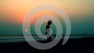 Silhouette of a child on a sunset background in the sea or ocean on a beach in summer during vacation in Goa, India