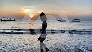 Silhouette of child walking in the beach during sunset