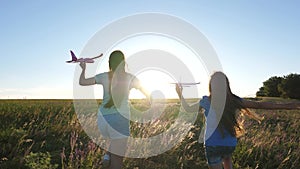 Silhouette of children playing on an airplane on a flower field. Dreams of flying. Happy childhood. Two girls play with