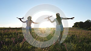 Silhouette of children playing on an airplane on a flower field. Dreams of flying. Happy childhood. Two girls play with