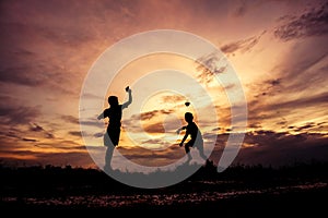 Silhouette of children playing paper airplane at sunset