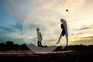 Silhouette of children playing paper airplane at sunset