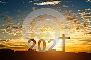 Silhouette of Christian cross with 2021 years at sunset background