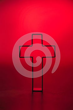 Silhouette of christian cross on red background, soft bokeh lights background. Copy space. Church worship, salvation