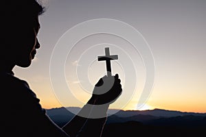 Silhouette of christian woman hand praying, woman holding a crucifix praying, spirituality and religion, woman praying to god.