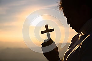 Silhouette of christian young women praying with a  cross at sunrise, Christian Religion concept background