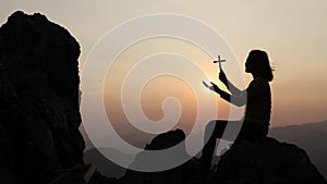 Silhouette of christianity woman catholic hand holding cross or crucifix pray to god at sunrise, person prayer in church concept