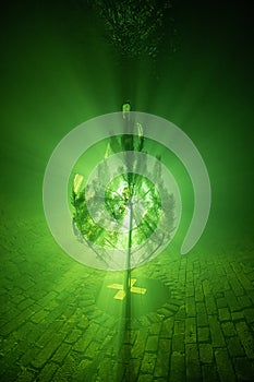 Silhouette of a Christmas tree in the fog, illuminated by green light, decorated with medical masks in the sewer tunnel