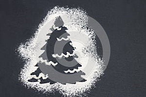 silhouette of a Christmas tree made of flour on a gray backgroun