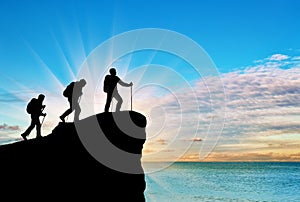 Silhouette climbers ascending to top of mountain