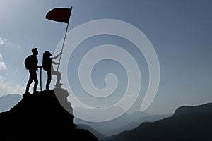Silhouette climbers with flag on mountain