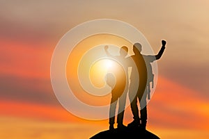 Silhouette of climbers man, hikers team celebration success happiness on a mountain top evening sky sunset / sunrise Background,