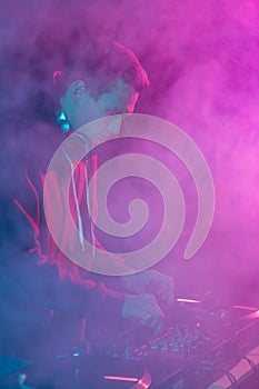 Silhouette of a club DJ playing music on a party. Cool white guy mixing vinyl records in night club