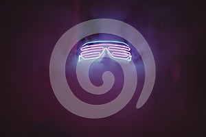 Silhouette of a clubber in neon glasses and smoke in a night club