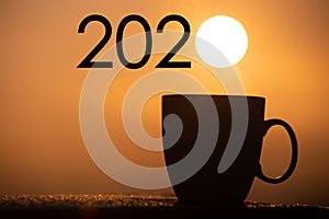 Silhouette coffee cup with new year 2020 text on a sunrise background