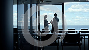 Silhouette colleagues talking panorama window office. Businessman leaving office