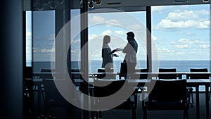 Silhouette colleagues talking panorama window office. Businessman leaving office