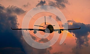 Silhouette of commercial airplane jetliner flying above dramatic clouds in beautiful sunset light. Travel concept