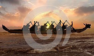 Silhouette of competitive people rowing dragon boat at sunset