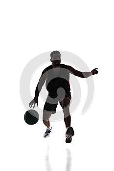 Silhouette of competitive young man, basketball athlete during game, training, dribbling ball isolated on white