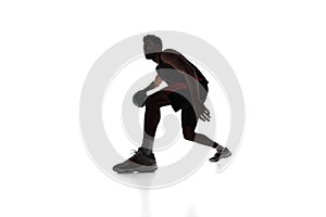 Silhouette of concentrated male athlete, basketball player in motion, dribbling ball isolated on white background