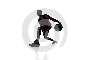 Silhouette of concentrated male athlete, basketball player in motion, dribbling ball isolated on white background