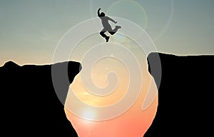 Silhouette concept idea.man jumping over cliff .