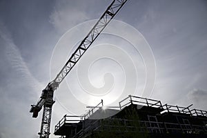 Silhouette of the construction crane in construction site with lens flare