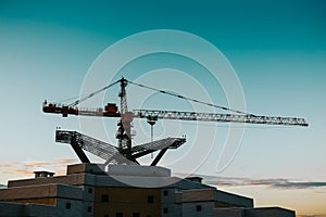 Silhouette of a construction crane over a high-rise building