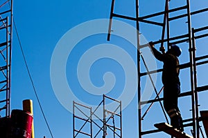 Silhouette of construction worker against sky on scaffolding wit