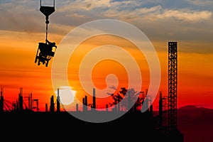 Silhouette construction worker on crane hook on sunset-sunrise time background and copy space