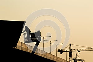 Silhouette of construction worker on scaffolding in the construction site before to night time