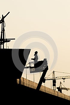 Silhouette of construction worker on scaffolding in the construction site before to night time