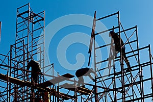 Silhouette of construction workers against sky on scaffolding wi