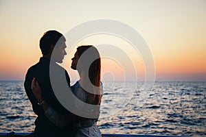 Silhouette of a couple at the beach at sunrise sky summer time, seashore summer beach at yellow blue evening horizon sea, sunset b