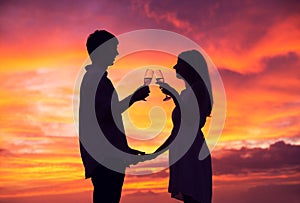 Silhouette of couple drinking champagne at sunset