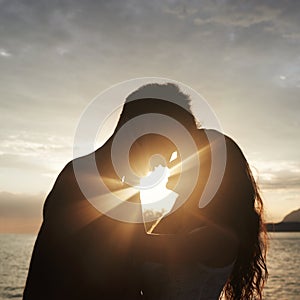 Silhouette, couple and face at ocean for sunset, vacation or travel together in summer on lens flare. Man, woman and