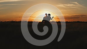 Silhouette of couple in golden field and beautiful sunset. Young and romantic family enjoying. Man hold woman in arms
