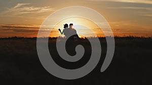 Silhouette of couple in golden field and beautiful sunset. Young and romantic family enjoying. Man hold woman in arms