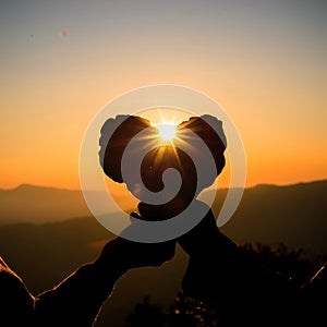 Silhouette of couple hands holding heart shape at the sky sunset background