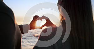 Silhouette, couple and heart hands, sunset at beach and love for bonding, romantic date outdoor with commitment. Man