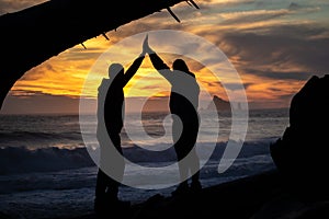 Silhouette of a couple high fiving at the beach during a beautiful sunset. Olympic National Park, Washington.