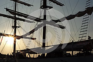 Silhouette of couple high mast on the big sailboat with clear sky of sunset in background