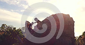 Silhouette of a couple hiking lending a helping hand. Hiker woman getting help from her male friend and overcoming an