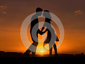 Silhouette of a couple holding hands at sunset